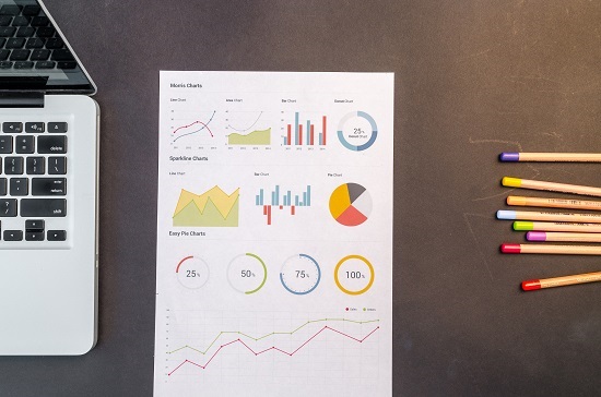 Image of a statistical report, colored pens, and Macbook